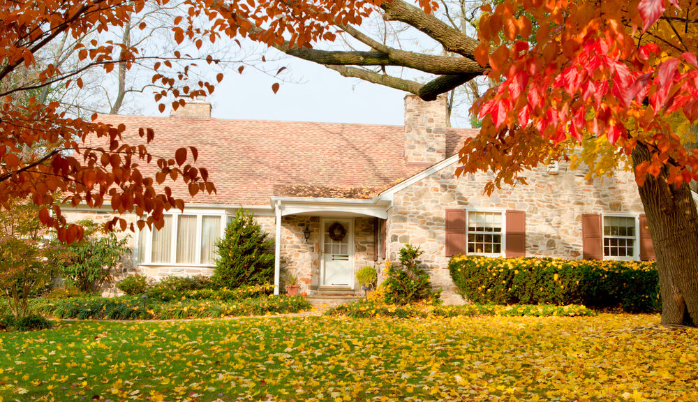 Single Family house with autumn leaves. Dogwood trees in the foreground, the yellow leaves are Norway Maple.