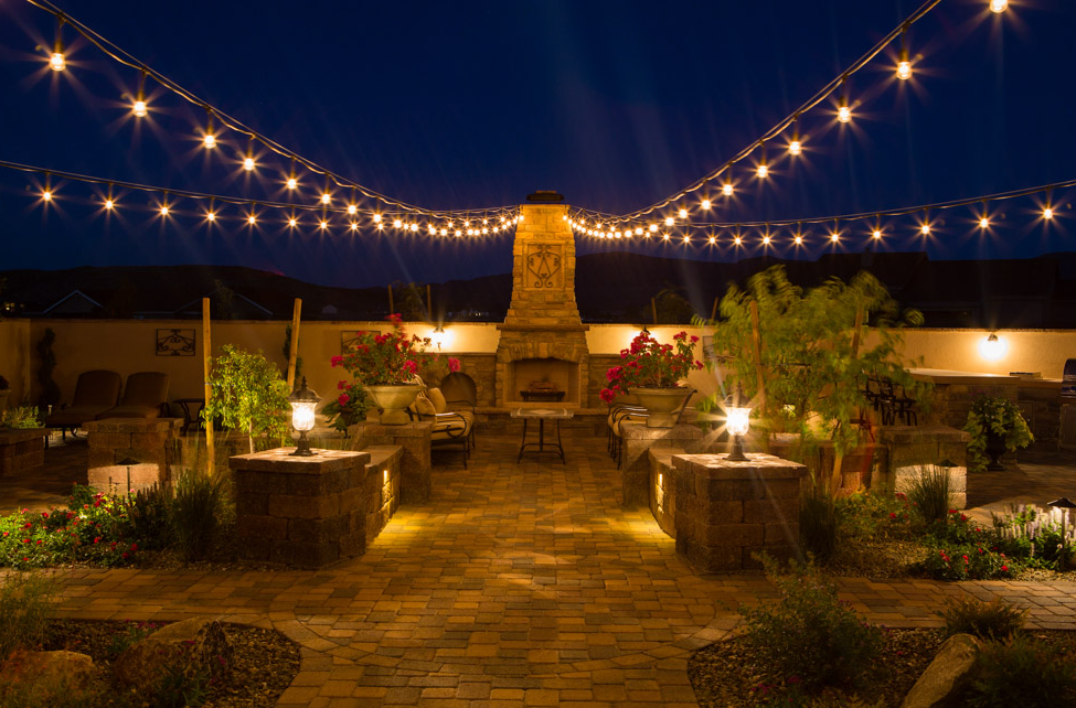 A fireplace and outdoor patio lit up in the evening that was redone by Vicente Landscaping in Northern Arizona